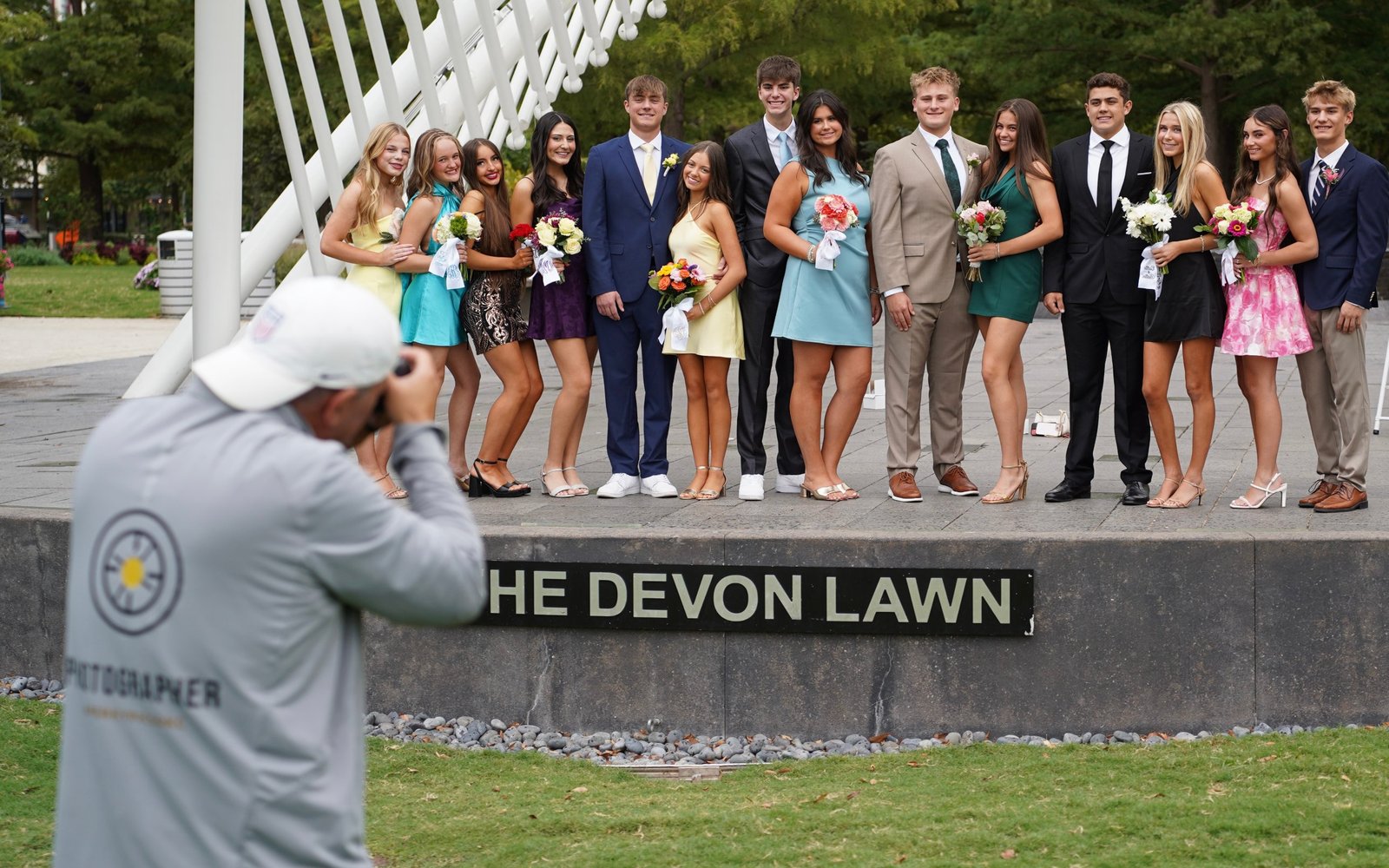 Perky Pics photographer shooting a formal group photo of students in dresses and suits at the Devon Lawn in Oklahoma City