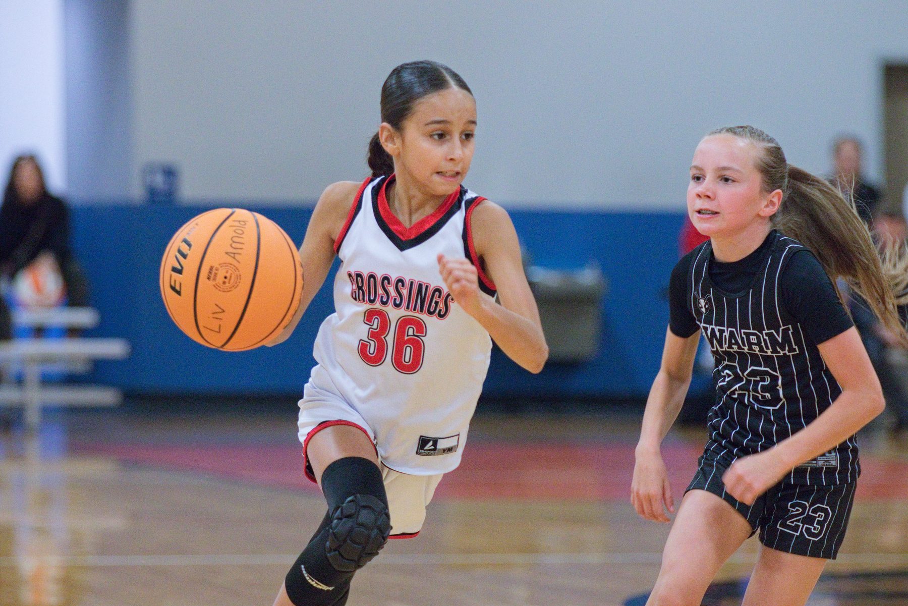 Girls basketball player dribbling up the court with a defender close behind