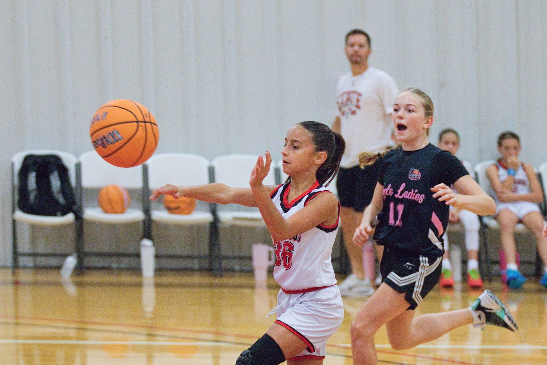 Basketball player throwing an outlet pass with a defender chasing