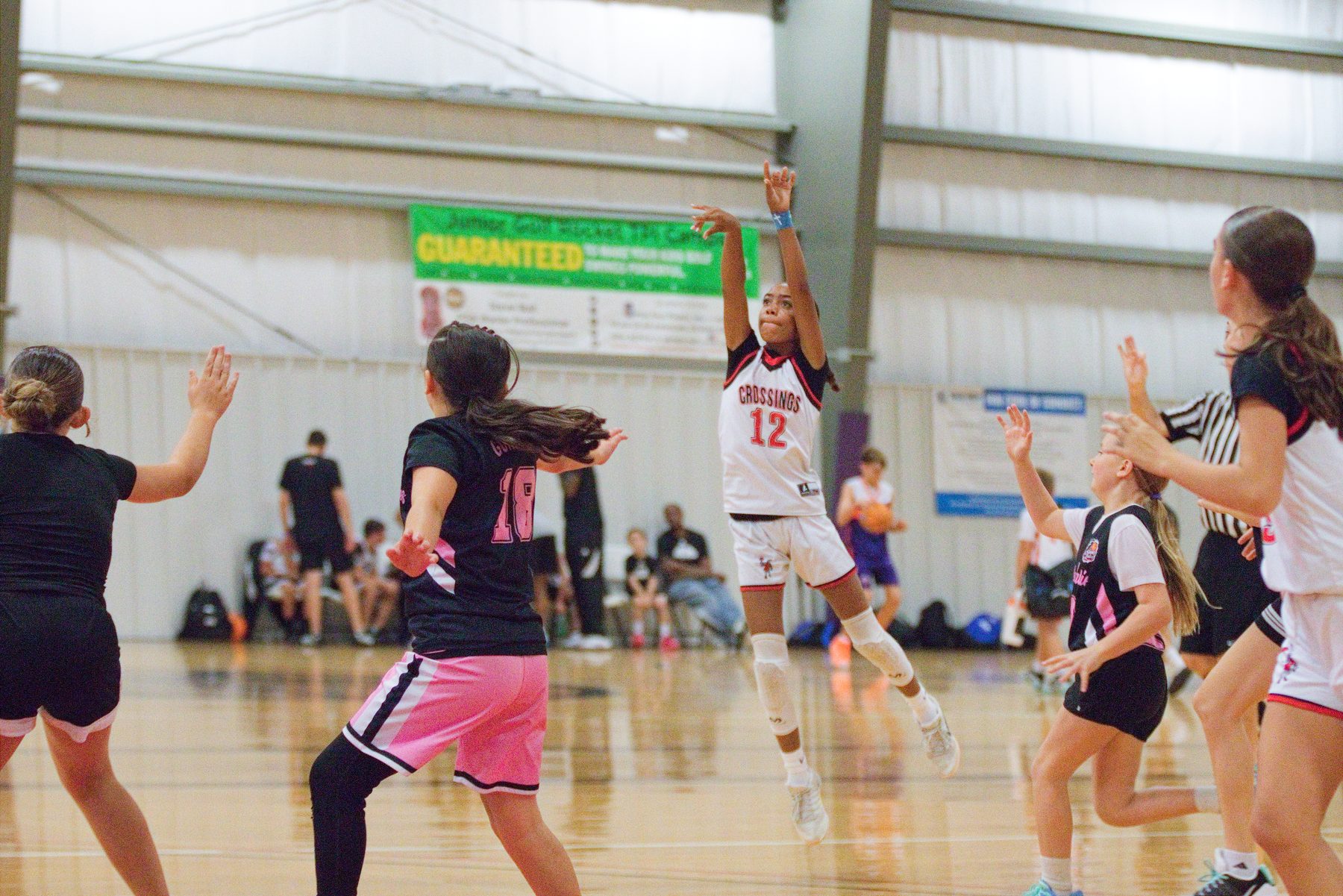 Basketball player leaping to defend a pass in a packed tournament gym