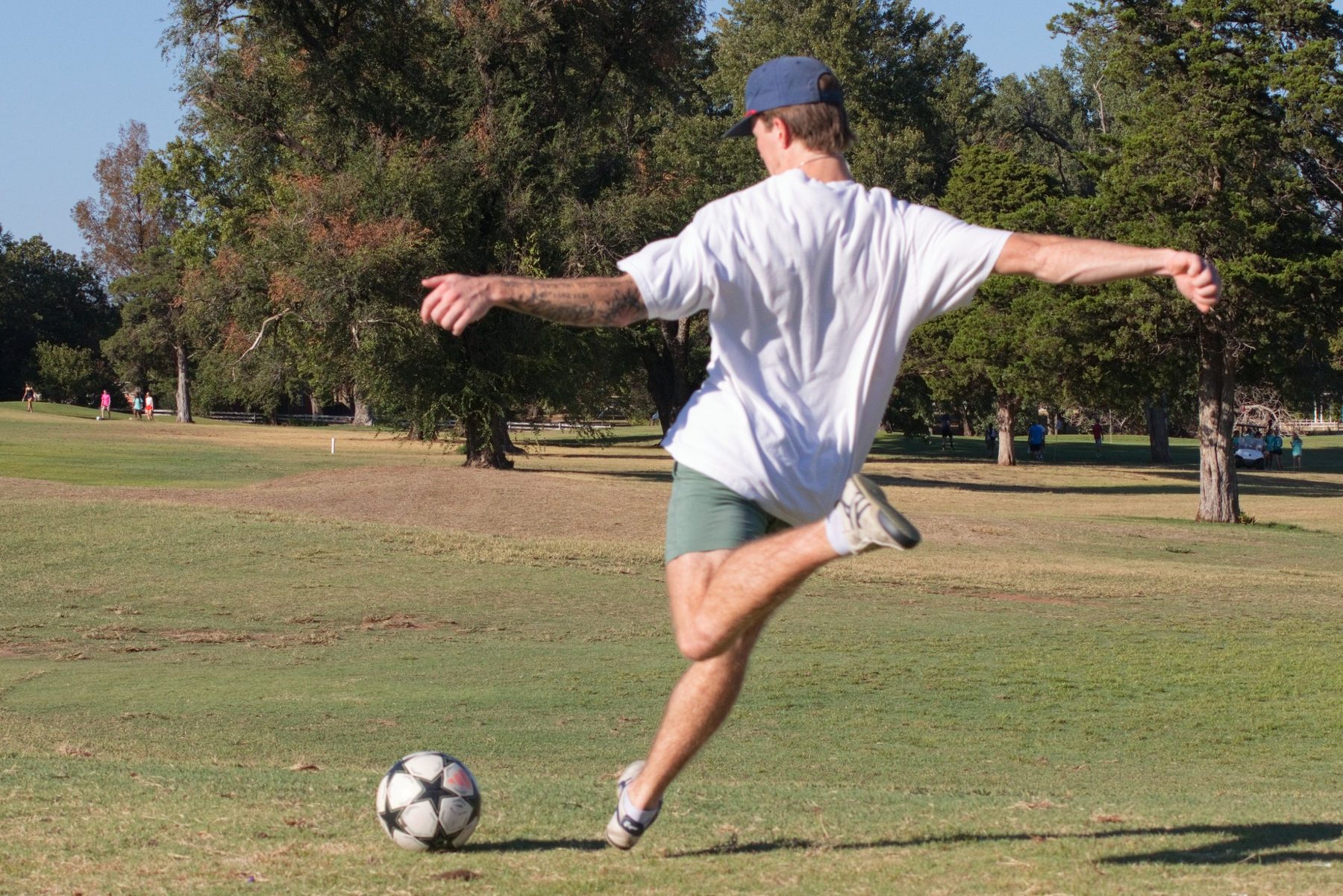 Foot golf player winding up to kick the ball down the fairway