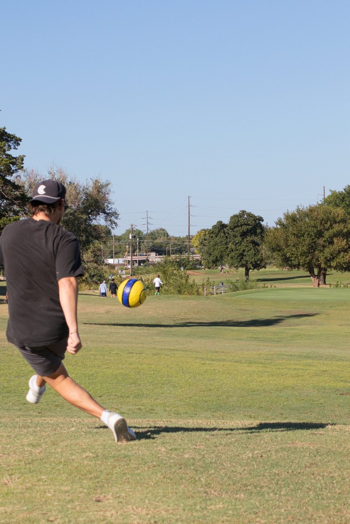 Foot golf player following through on a kick with the ball in flight