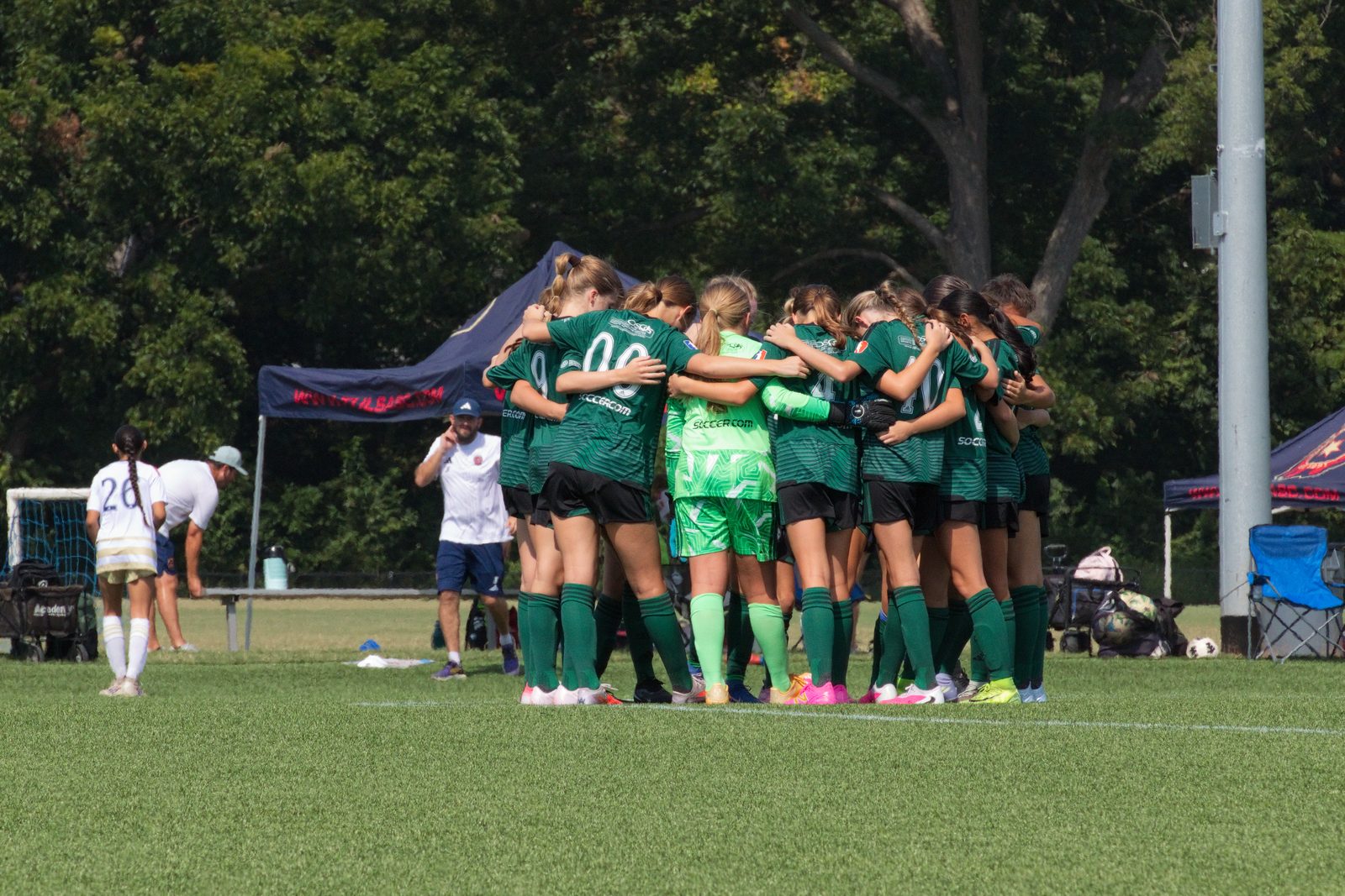 Youth soccer team huddled together on the field during a game